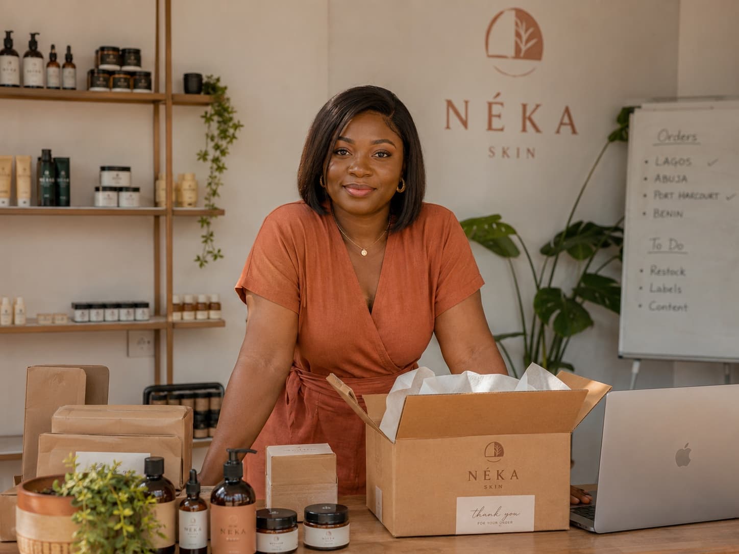 A skincare merchant in her studio with products and packed orders